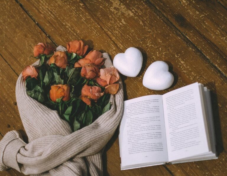 Romantic arrangement of roses, book, and hearts on a wooden surface, perfect for Valentine's ambiance.